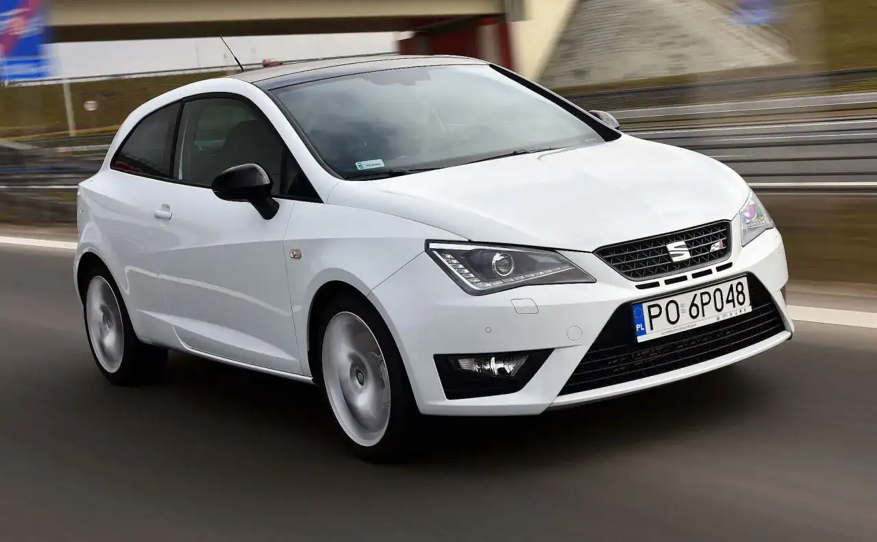 Biały Seat Ibiza 1.4 benzyna pędzi po drodze, z czarnym dachem i felgami.