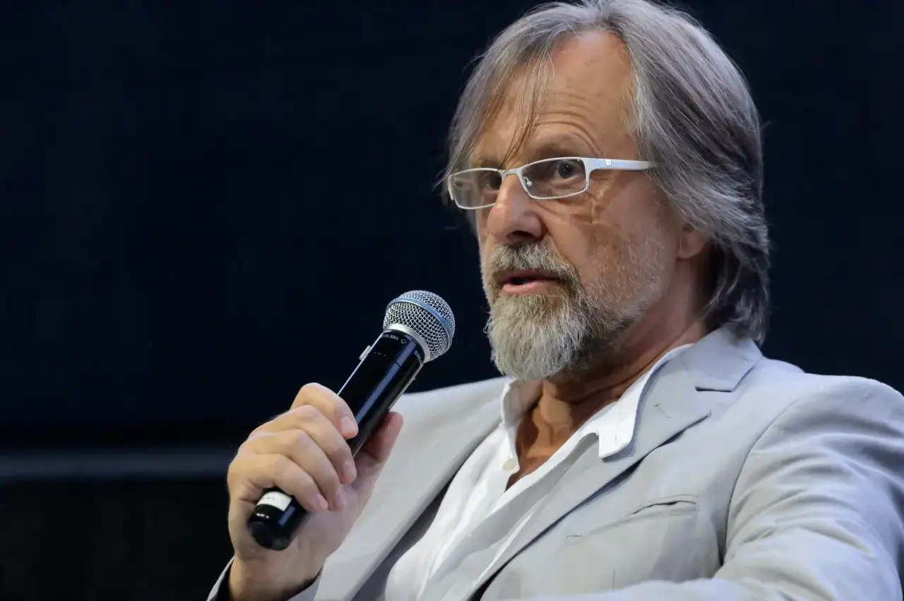 Mężczyzna w okularach i jasnej marynarce trzyma mikrofon. Człowiekiem jestem i nic co ludzkie nie jest mi obce, nawet gdy przemawiam do tłumu.