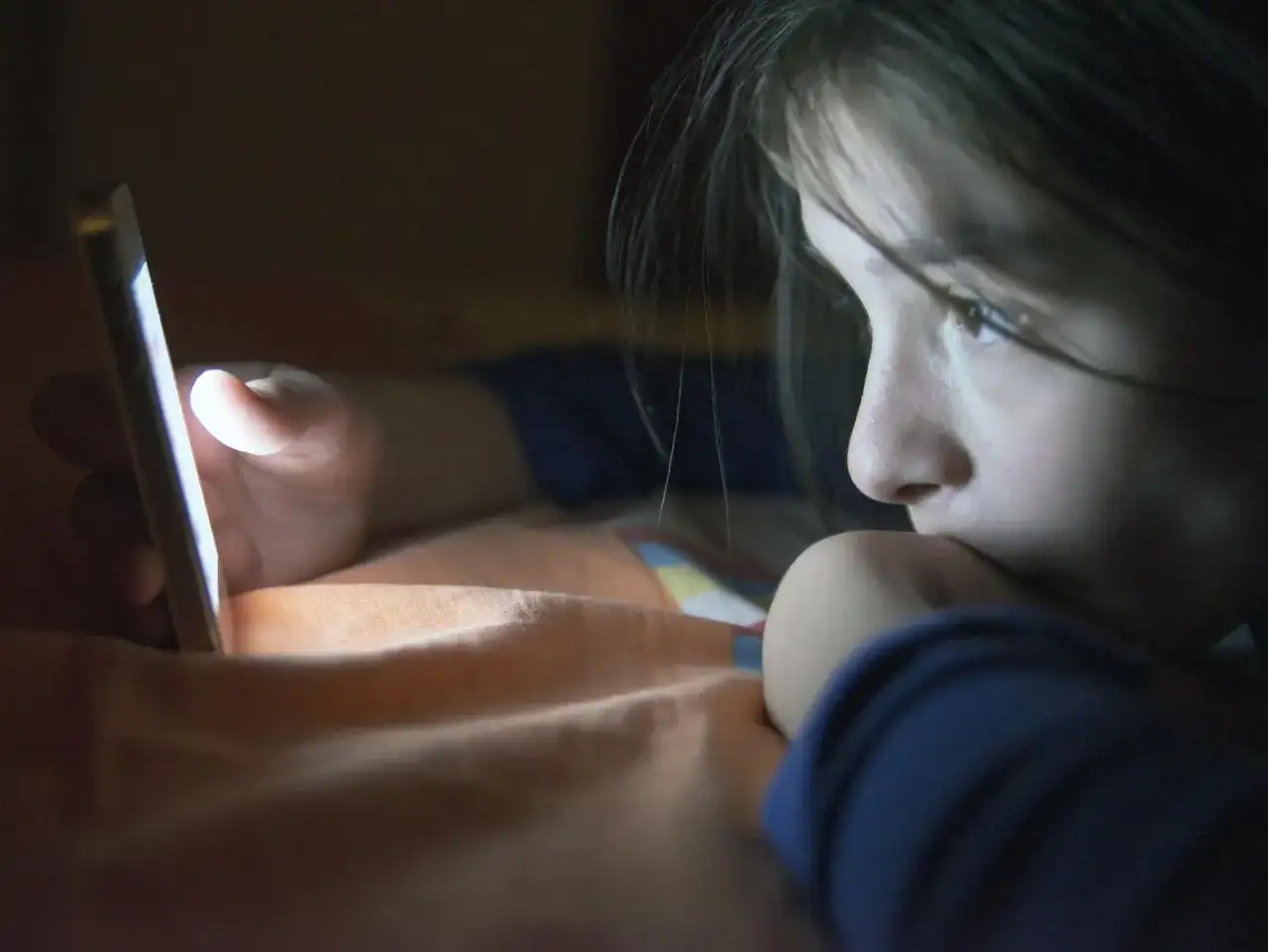 Dziecko wpatrzone w ekran telefonu. Jak influencerzy radzą sobie z hejtem skierowanym w stronę ich dzieci?