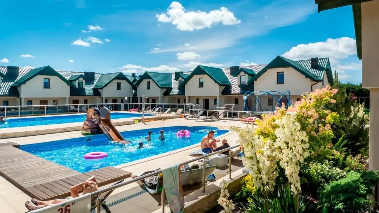 Rodzinny wypoczynek w domkach apartamentowych Fulay Premium. Dzieci bawią się w basenie ze zjeżdżalnią, dorośli relaksują się na leżakach.