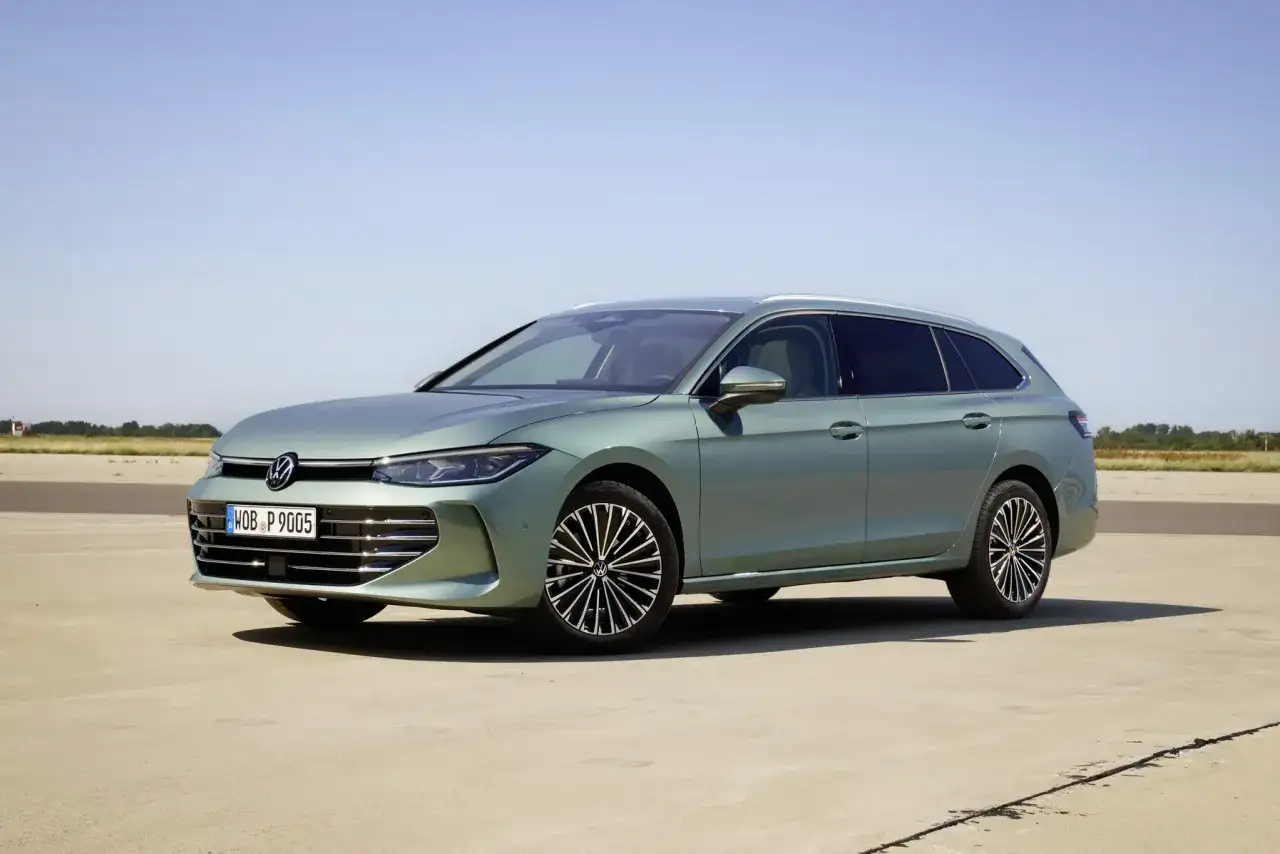 Nowy Volkswagen Passat B9 w kolorze zielonym, zaparkowany na betonowej nawierzchni, z błękitnym niebem w tle.