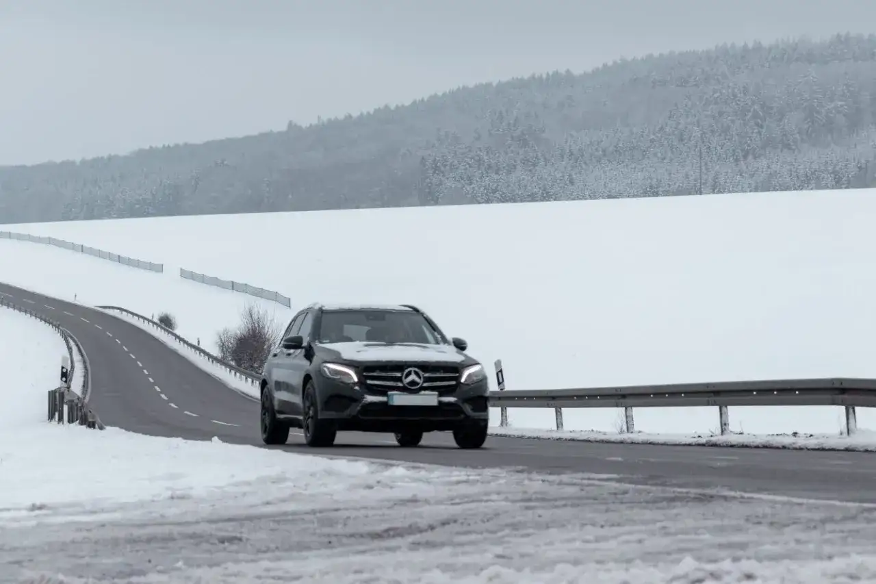 Czarny Mercedes GLE jedzie po ośnieżonej drodze. Jego wymiary pozwalają na pewne poruszanie się w trudnych warunkach.