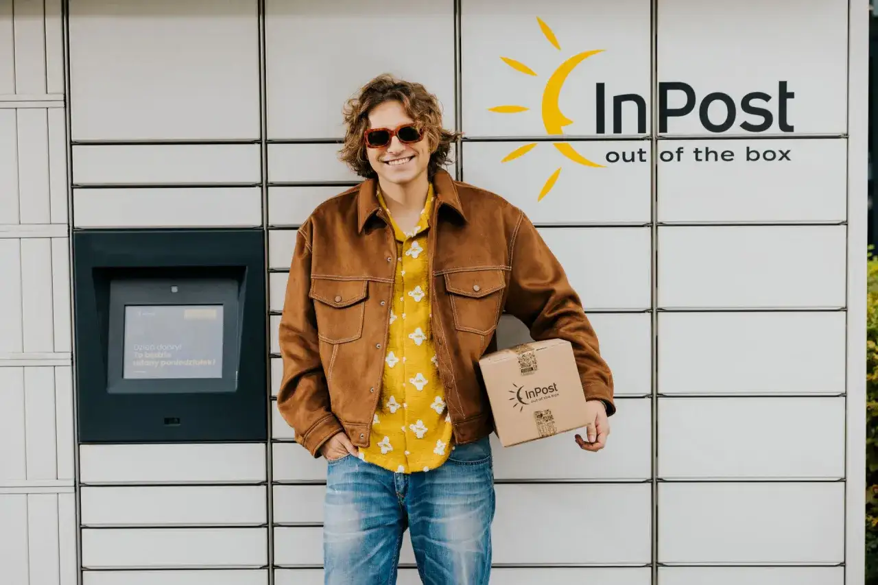 Uśmiechnięty mężczyzna z paczką InPost. Wysłał ją w piątek, więc pewnie dojdzie w poniedziałek.