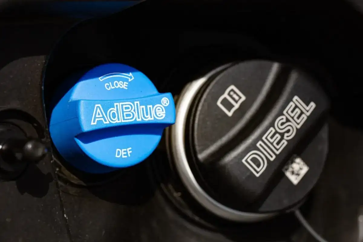 Le bouchon bleu indique "AdBlue", un liquide essentiel pour les moteurs diesel modernes. À côté, le bouchon noir est marqué "DIESEL".