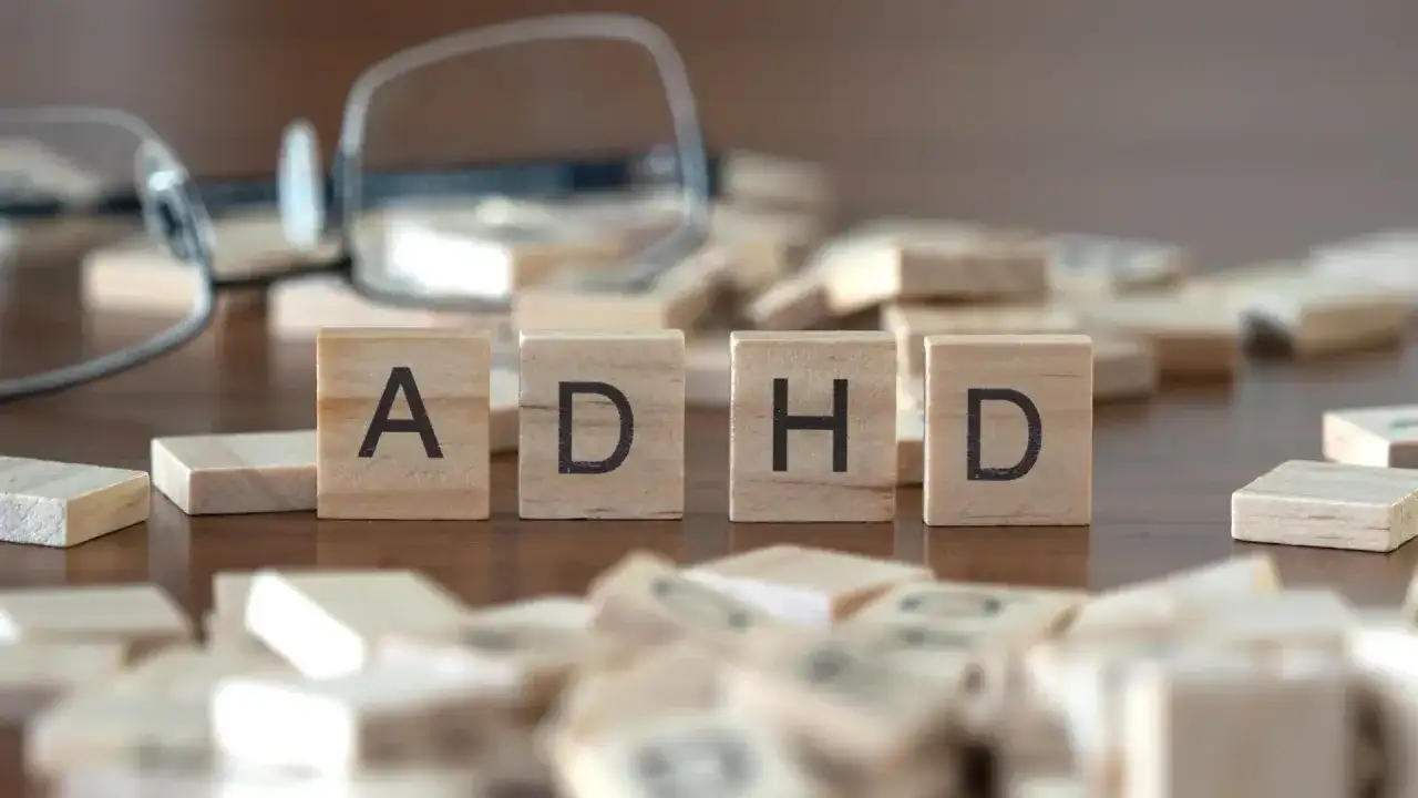 Drewniane klocki z literami "ADHD" i rozrzucone po stole, sugerujące poszukiwanie rozwiązań, np. leki na ADHD.