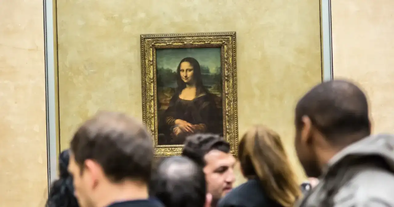 Mona Lisa z Isleworth, otoczona tłumem widzów, spogląda tajemniczo ze złotej ramy.