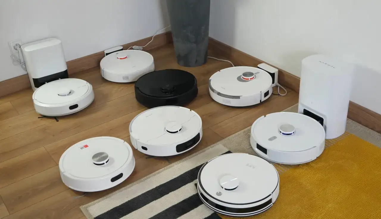 Ranking robotów sprzątających: białe i czarne modele na drewnianej podłodze, gotowe do testów.