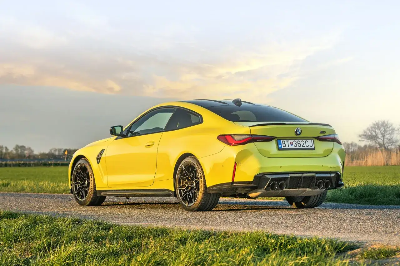 Żółte BMW M4 Competition na tle zachodzącego słońca. Sprawdź aktualną bmw m4 competition cena.