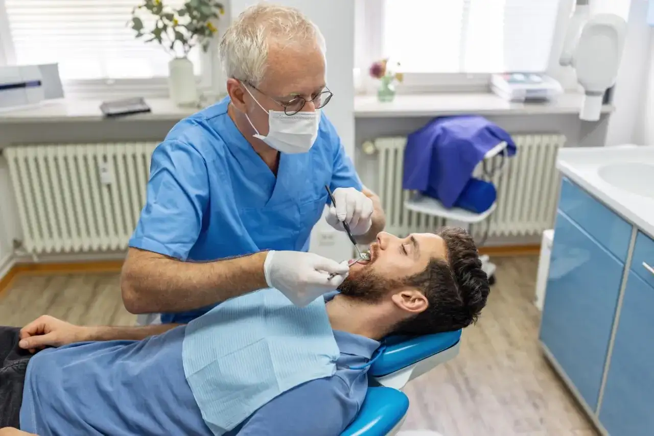 Dentysta bada pacjenta. Zastanawiasz się, ile kosztuje usunięcie ósemki na NFZ? Wizyta u stomatologa to pierwszy krok.