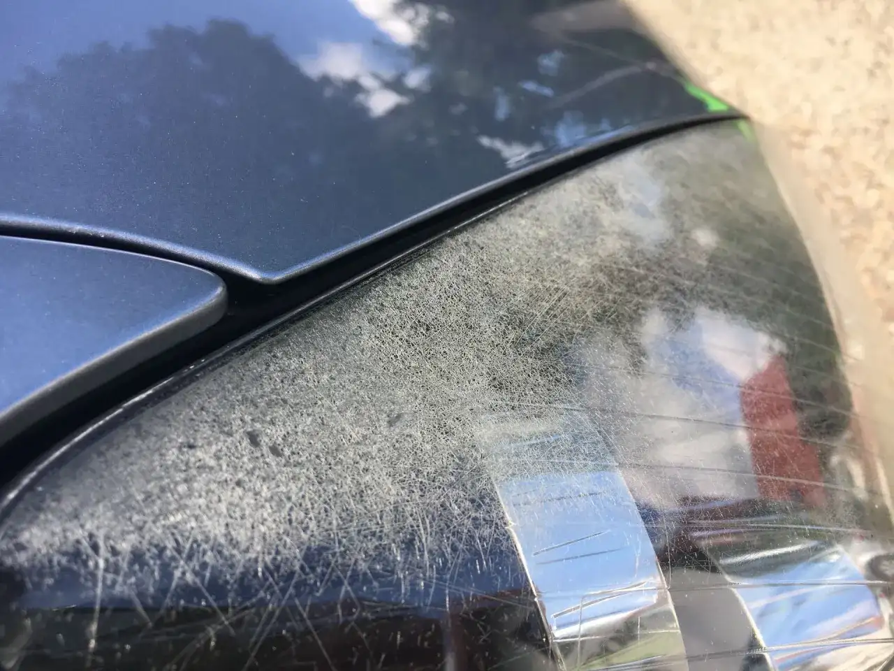 Głębokie rysy na reflektorze samochodu, świadczące o jego zużyciu.