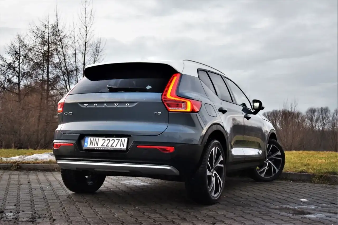 Tylny widok na ciemnoszary Volvo XC40 T3 z białym dachem, zaparkowany na brukowanej nawierzchni.