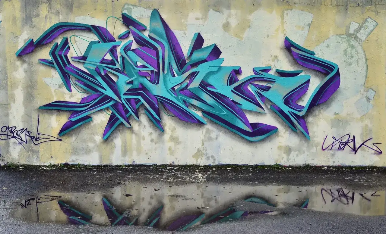 Wielobarwne, przestrzenne graffiti w odcieniach turkusu i fioletu zdobi ścianę. To przykład sztuki ulicznej, która często jest formą wyrazu artystycznego.
