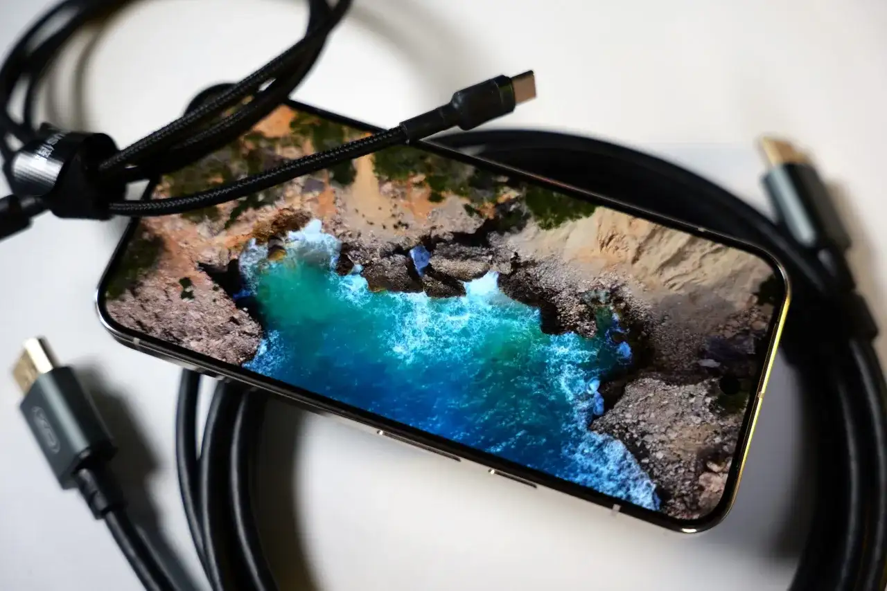 Telefon z widokiem na morze, podłączony kablem USB-C. Obraz z telefonu na TV przez USB-C to łatwy sposób na przeniesienie wrażeń.