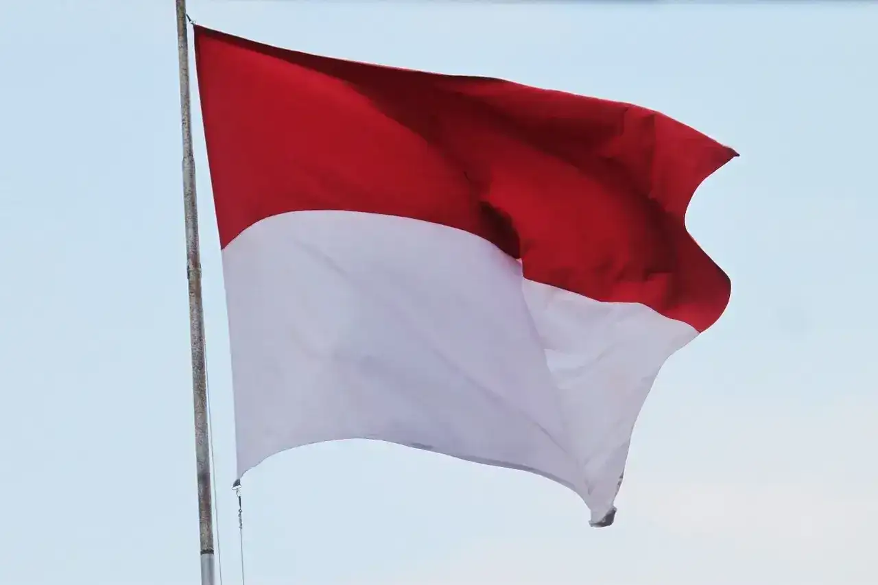 Flaga Indonezji powiewa na wietrze, ukazując swoje dumne czerwono-białe barwy na tle błękitnego nieba.