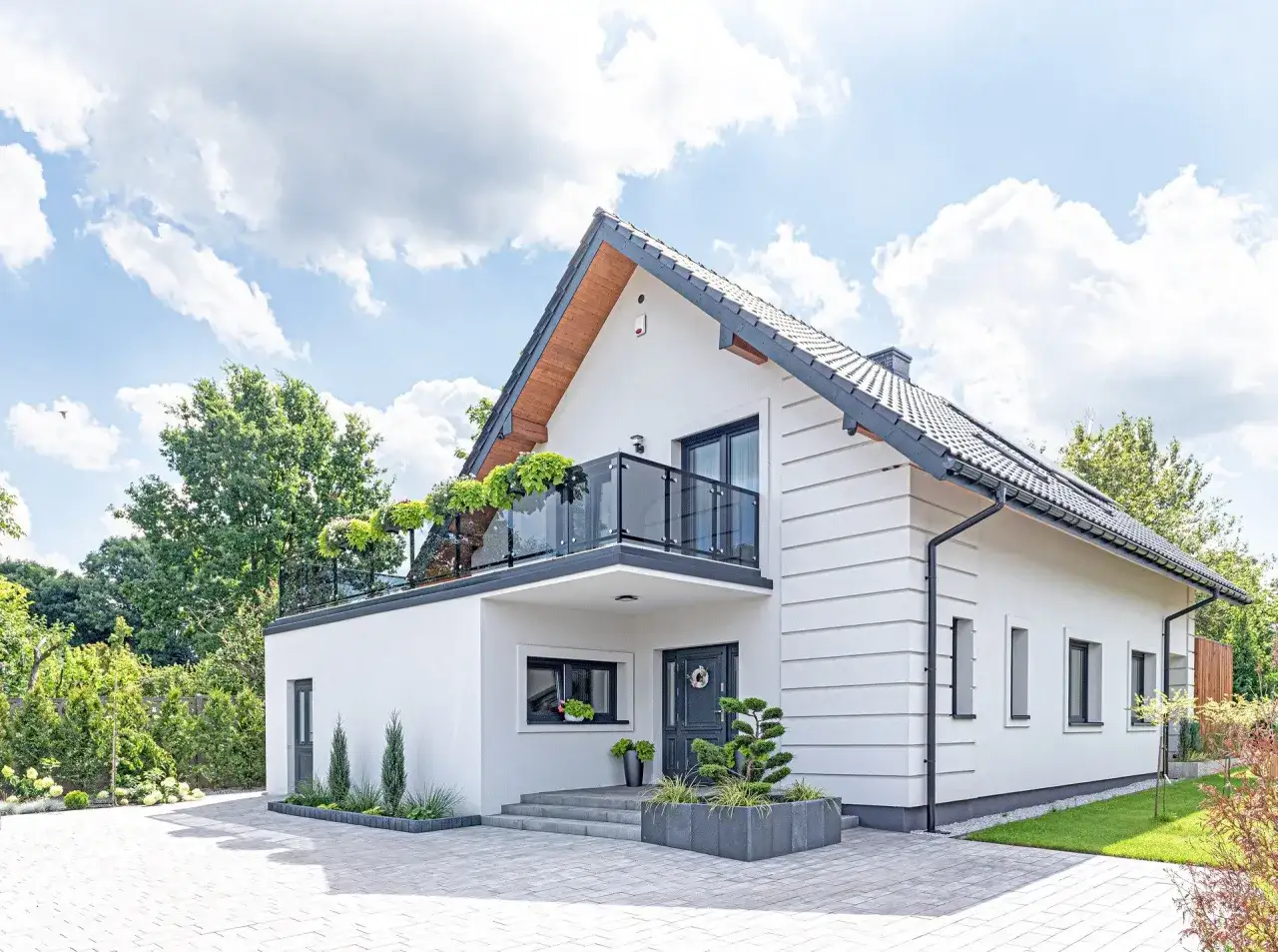 Nowoczesny biały dom z balkonem i zielenią. Idealne miejsce na realizację darmowe projekty domów.