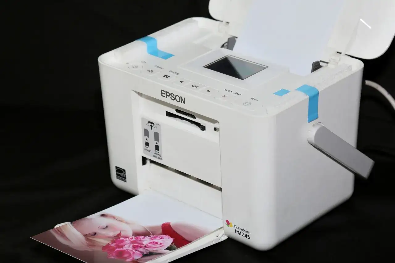 Biała drukarka Epson PictureMate PM 245 drukuje zdjęcie kobiety z różami. Szukasz, jaka drukarka najtańsza w eksploatacji?