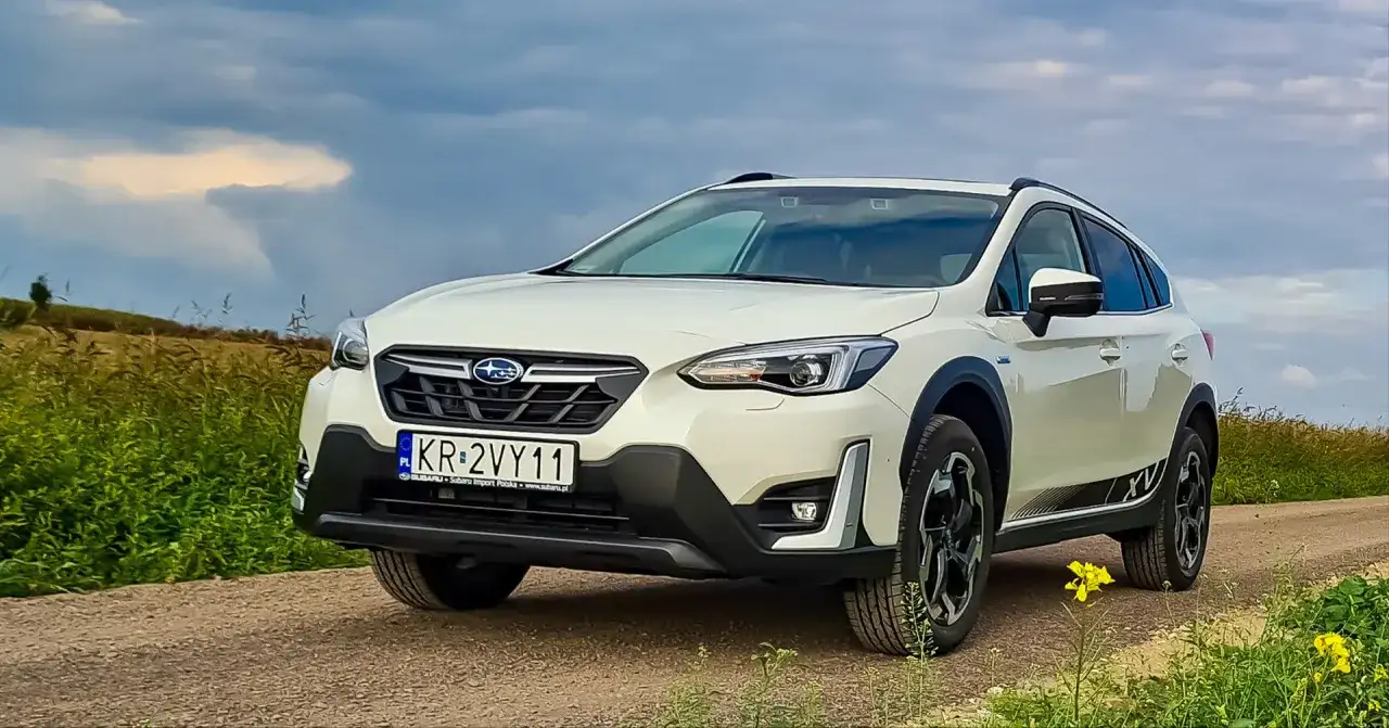 Biały Subaru XV na drodze polnej, z polami w tle. Rozważasz zakup? Sprawdź wady i zalety tego modelu.