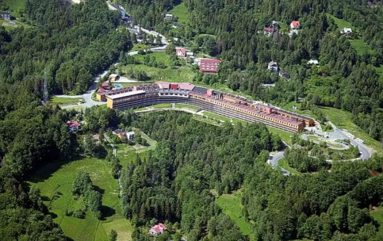 Widok z lotu ptaka na Orle Gniazdo w Szczyrku, rozległy budynek hotelowy otoczony zielonymi lasami i polanami.