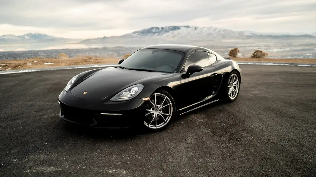 Czarny Porsche GTS na tle gór i jeziora.