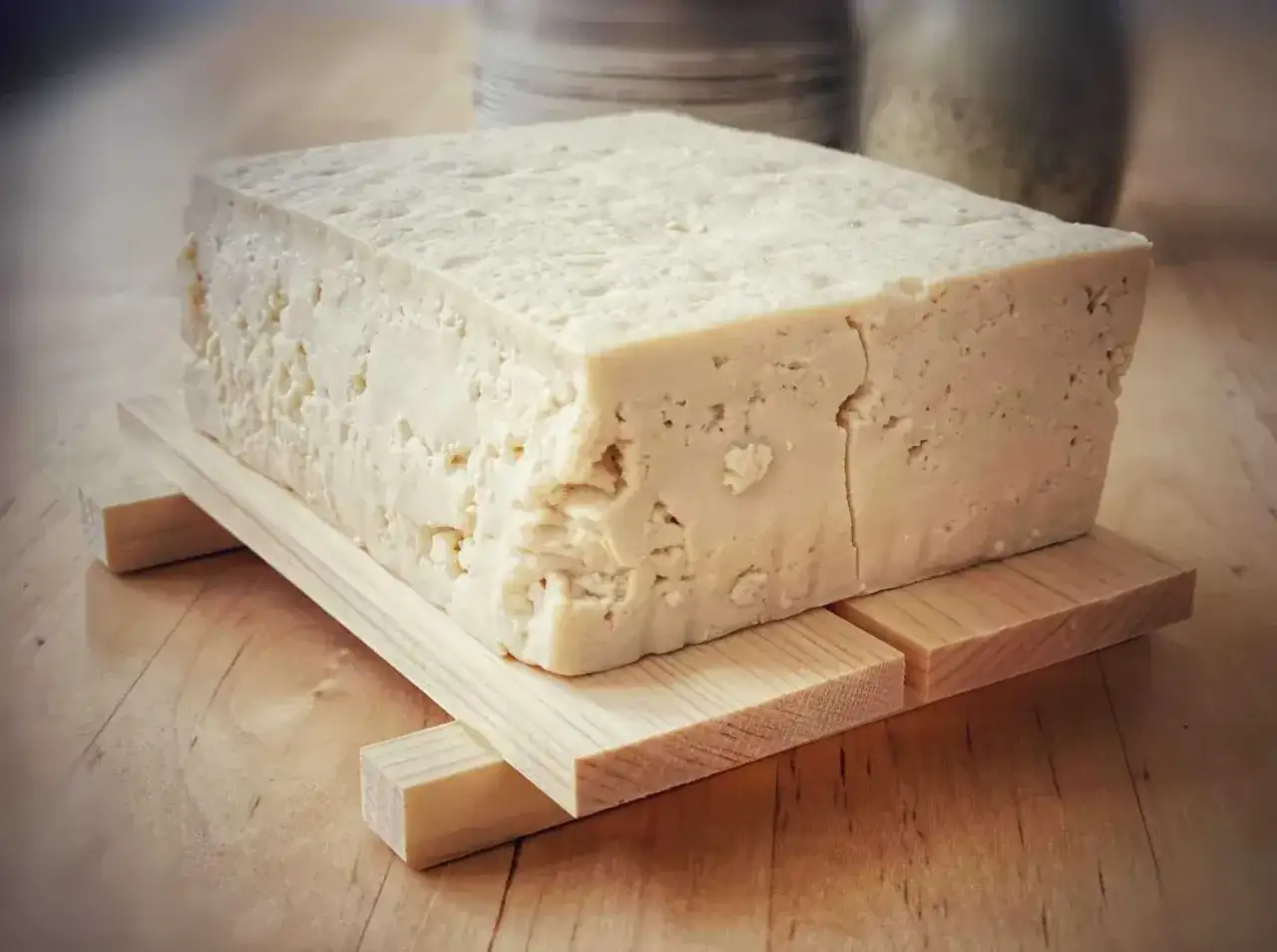 Duży blok domowego, białego tofu na drewnianej podstawce.