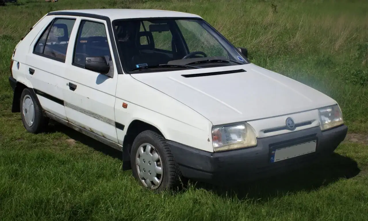 Biały Skoda Favorit stoi na trawie.