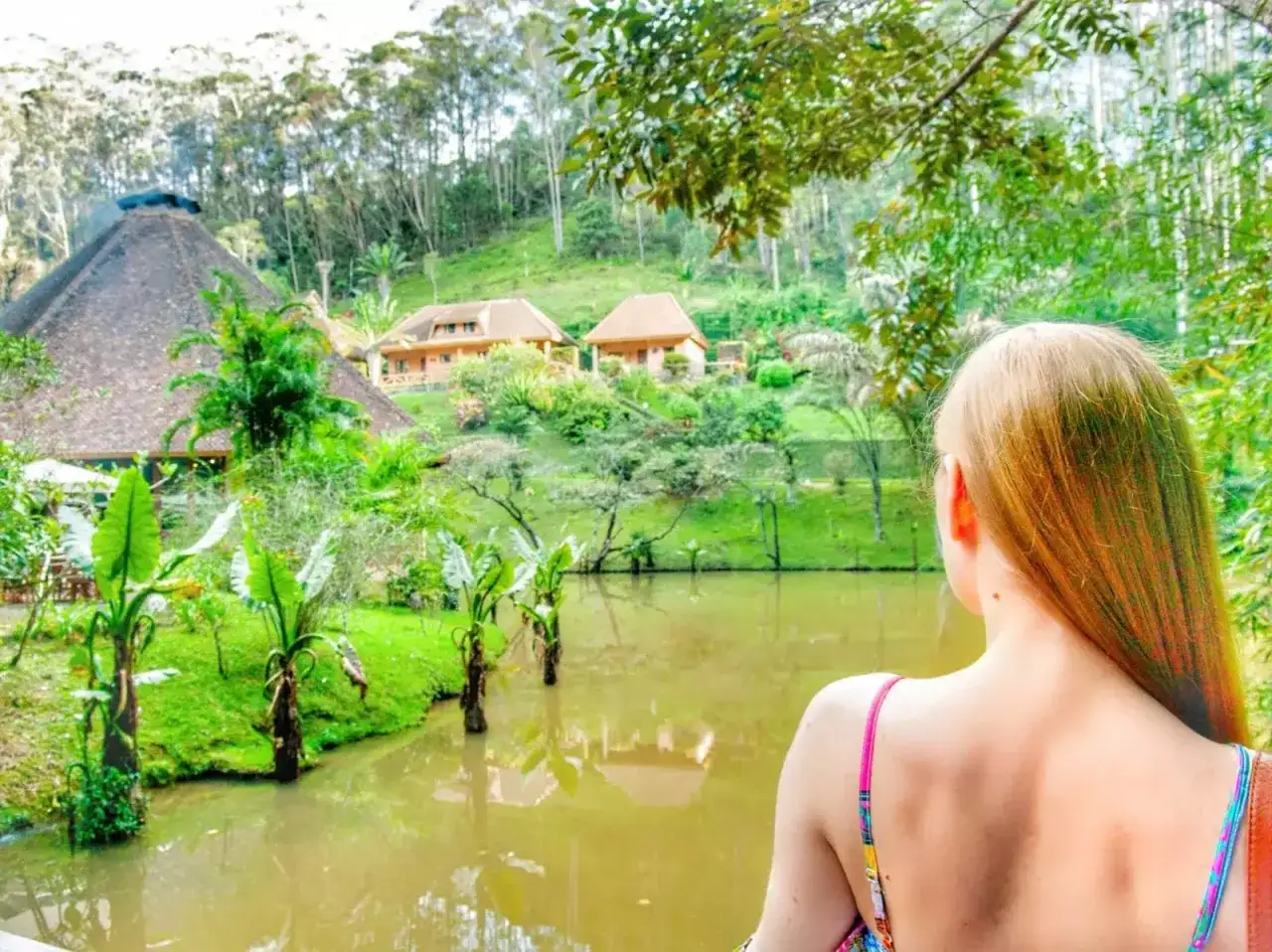 Dziewczyna podziwia tropikalny krajobraz z jeziorem i domkami. Idealne **Madagaskar wakacje**!