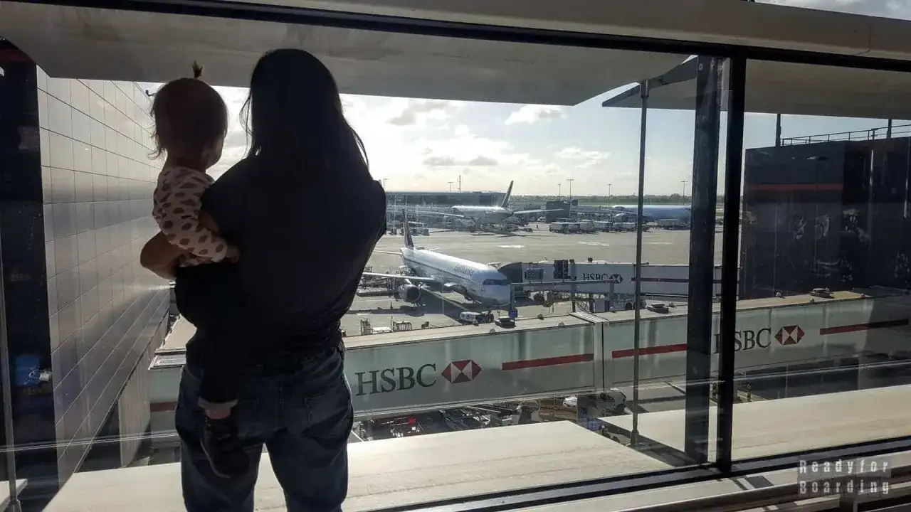 Mama z dzieckiem na rękach patrzy na samoloty. Czas na boarding, przygoda czeka!