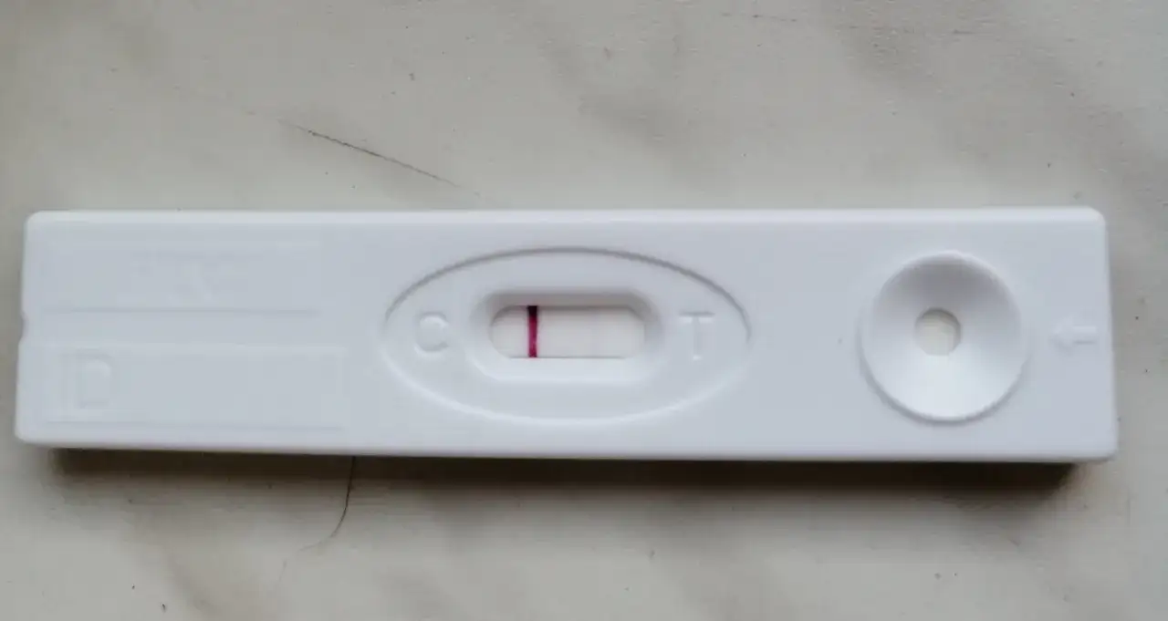 Blada kreska na teście ciążowym, widoczna przy literze "C", sugeruje wynik negatywny.