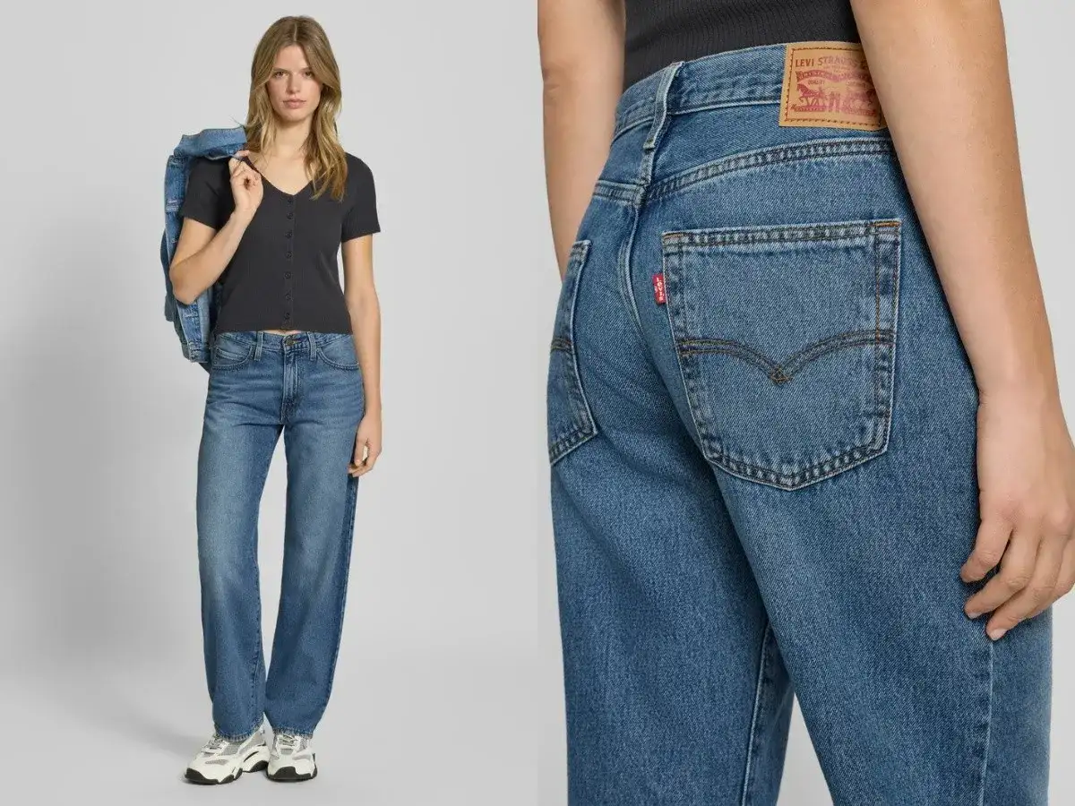Modelka w jeansach Levi's i czarnej bluzce, z kurtką dżinsową na ramieniu. Detal zbliżenia na tył spodni z charakterystyczną czerwoną metką.