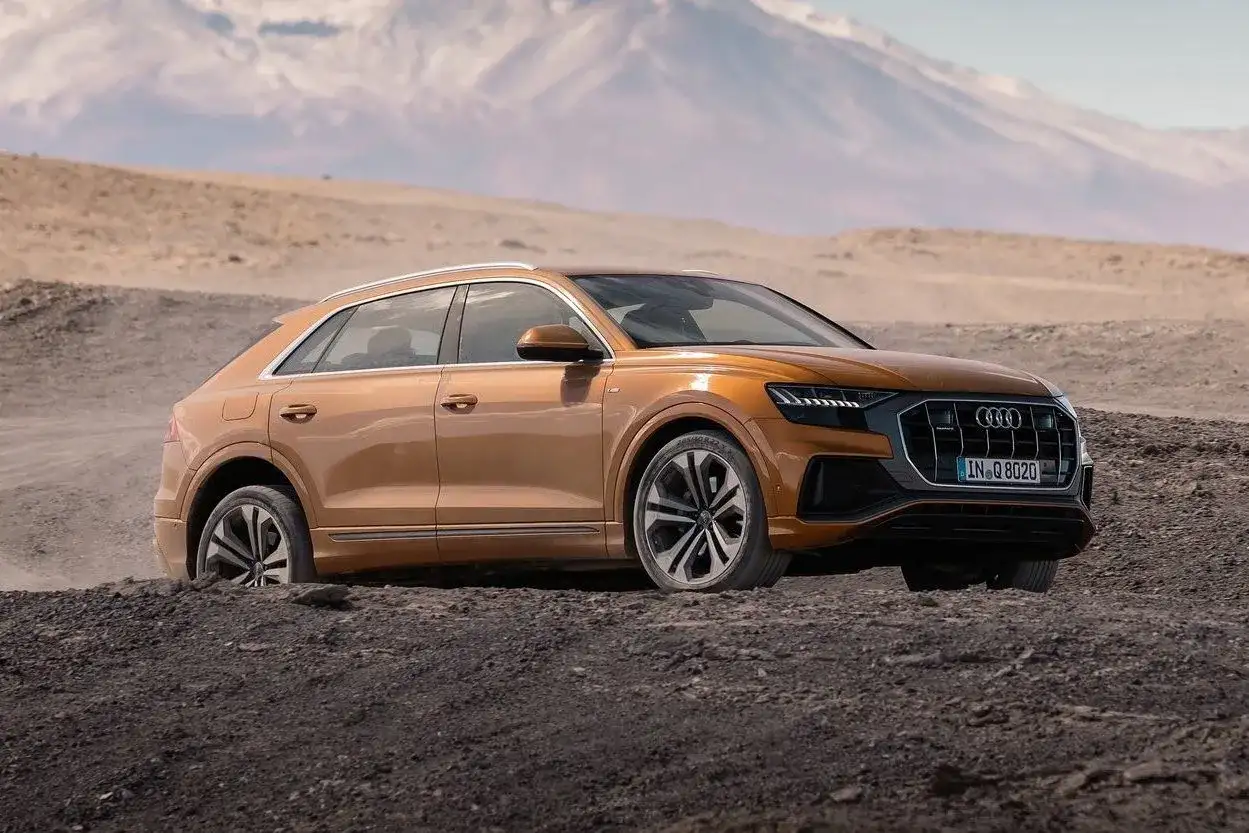 Pomarańczowy Audi Q8 w terenie, gotowy na przygodę. Sprawdź aktualną audi q8 cena i odkryj jego możliwości.