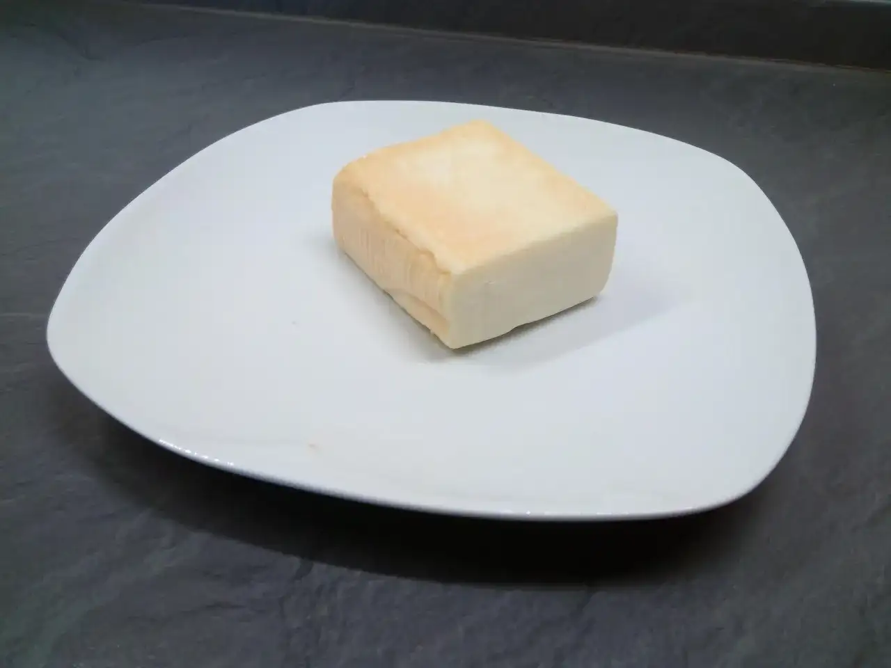 Kawałek sera taleggio na białym talerzu. Czy taleggio to dobry wybór na przekąskę?