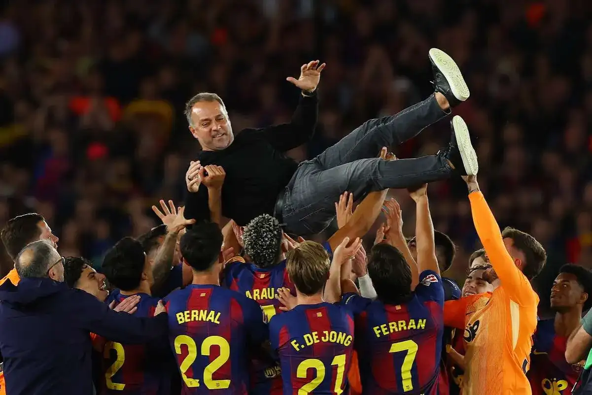 Piłkarze FC Barcelona 22/23 unoszą trenera Xaviego w geście radości po wygranym meczu.