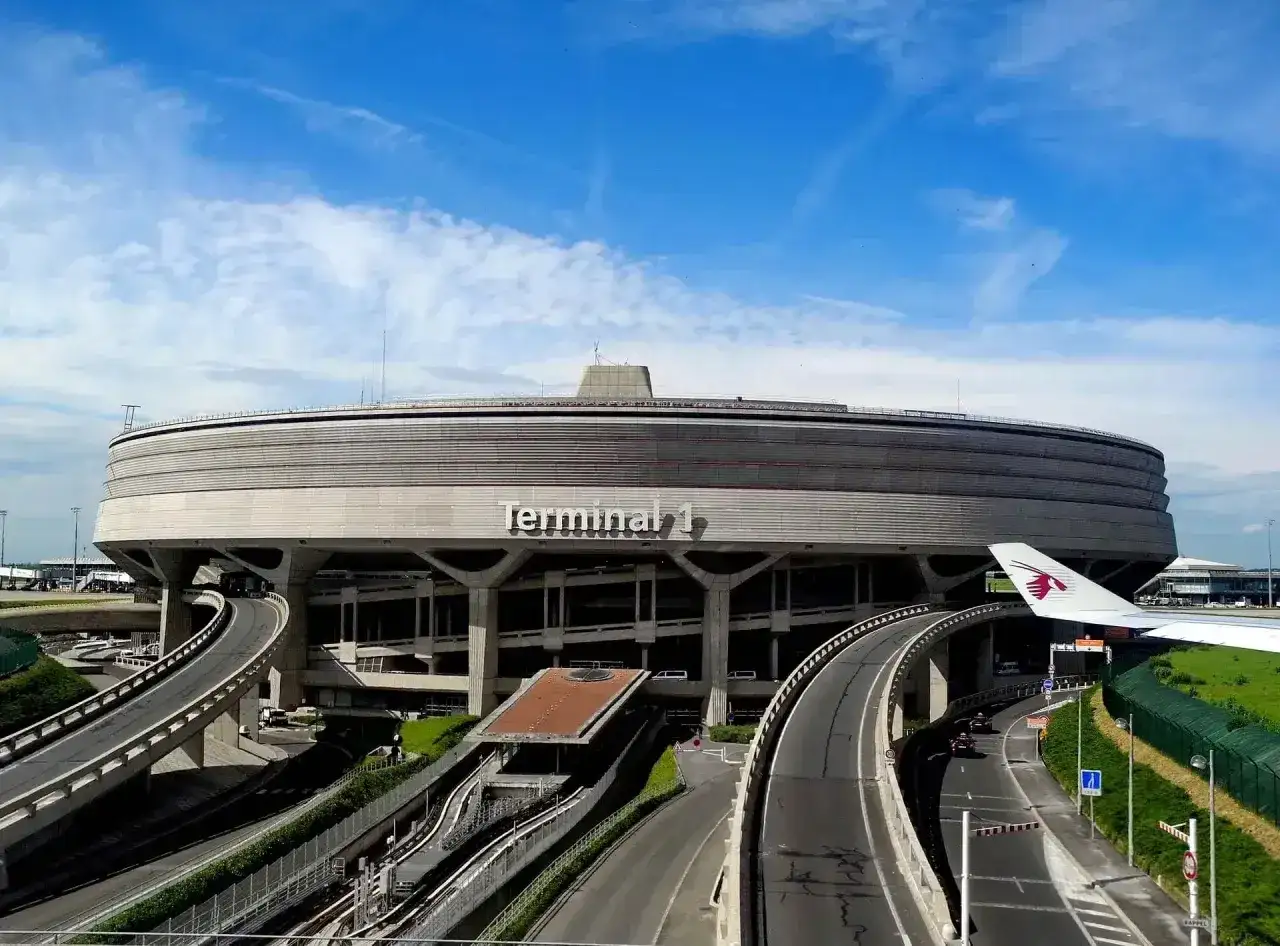 Charakterystyczny Terminal 1 na lotniskach w Paryżu, z krętymi drogami i fragmentem samolotu Qatar Airways.