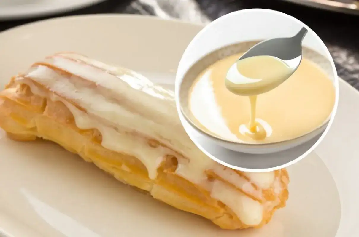 Słodki ekler oblany lukrem, obok miseczka z kremowym custard. Pyszny deser!