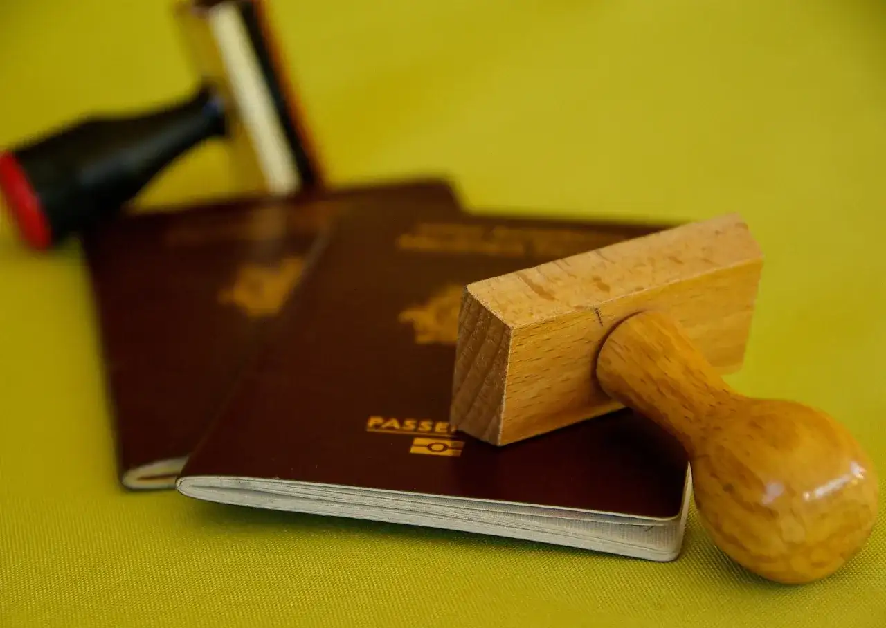 Pasporty i pieczątki, symbolizujące podróże, ale też potencjalną deportację.