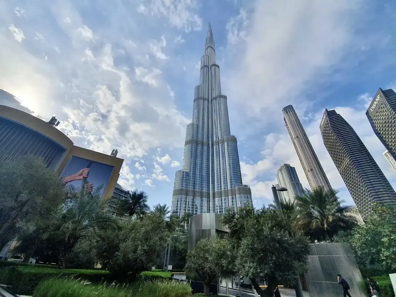 Majestatyczny Burj Khalifa w Dubaju wznosi się ku niebu, otoczony nowoczesnymi wieżowcami i zielenią.