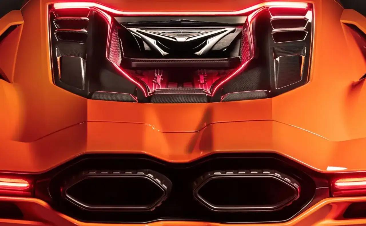 Pomarańczowy Lamborghini Revuelto z widocznym silnikiem i czerwonym podświetleniem.