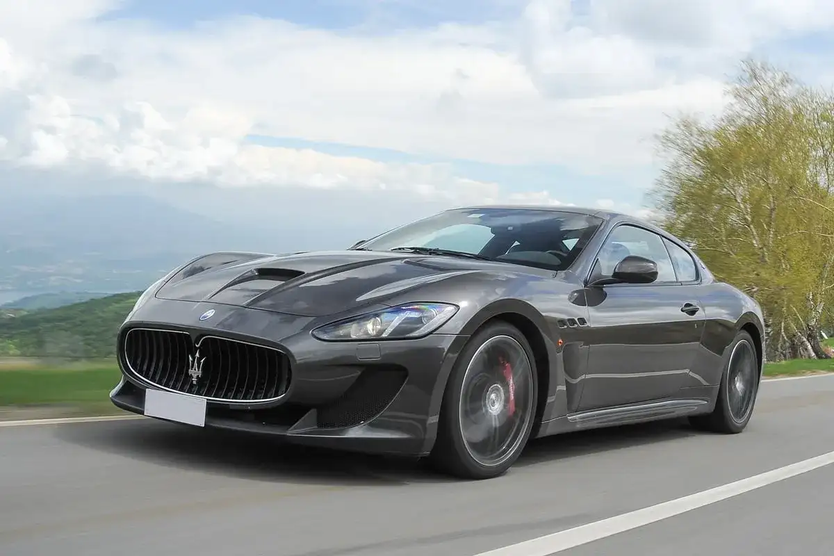 Szary Maserati GranTurismo na krętej drodze. Marzysz o takim aucie? Sprawdź aktualną maserati cena i spełnij marzenie.