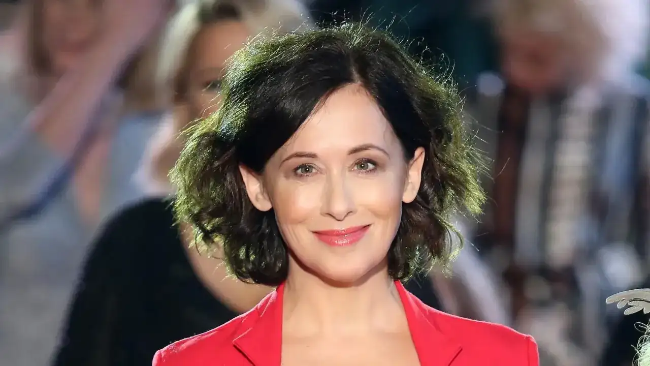 Uśmiechnięta Jolanta Fraszyńska w czerwonej marynarce, znana z wielu filmów, seriali i programów.