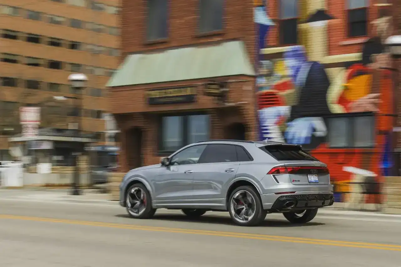 Srebrny Audi RS Q8 pędzi ulicą obok kolorowego muralu. Sprawdź aktualną audi rsq8 cena i możliwości tego SUV-a.