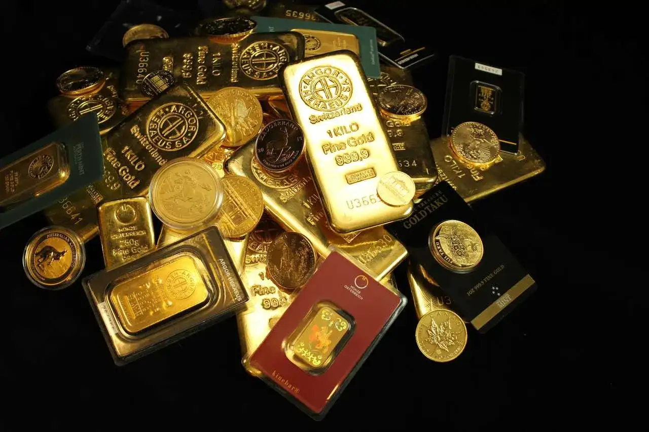 Złote sztabki i monety, w tym 1-kilogramowa sztabka, pokazują, ile waży sztabka złota.