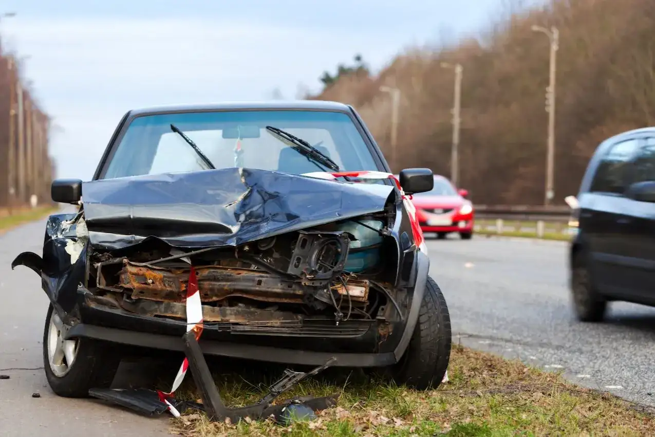 Un coche negro destrozado en la carretera, parece que fue un accidente grave. Un punto negro en la carretera que nadie quiere ver.