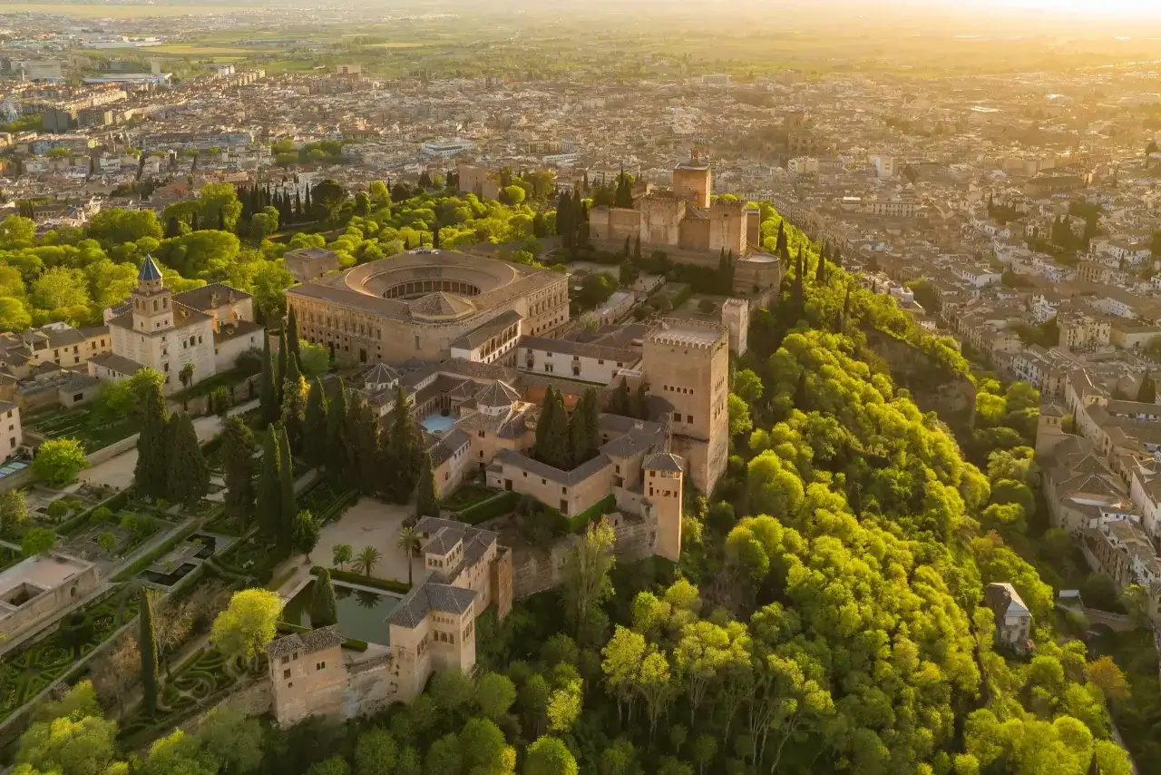 Widok z lotu ptaka na Alhambrę w Granadzie, otoczoną bujną zielenią. Marzysz o zwiedzaniu? Sprawdź alhambra bilety!
