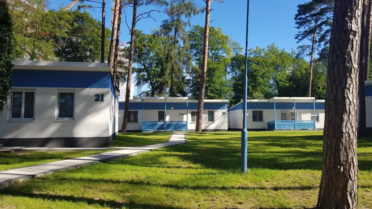 Urocze domki letniskowe w Międzyzdrojach, otoczone zielenią, zapraszają na wypoczynek. Numer 21 widoczny na jednym z budynków.