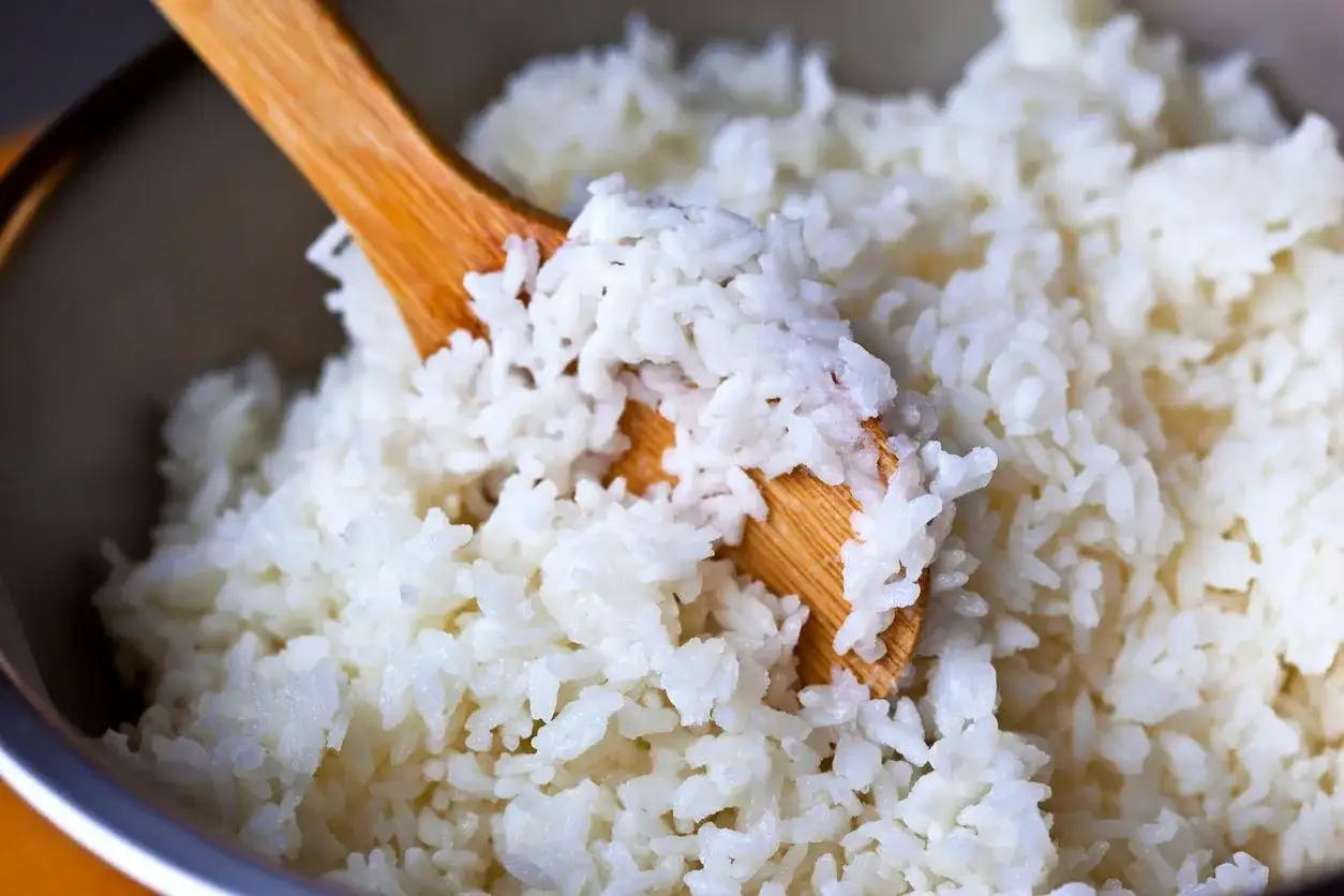 Drewniana łyżka miesza puszysty, biały ryż. Idealny do sushi, wygląda na bardzo dobry ryż.