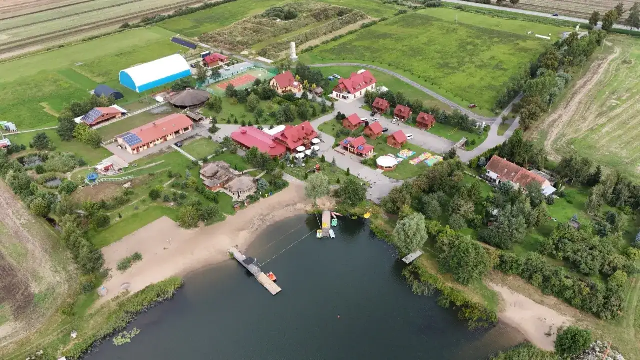 Malownicza jeziorna osada Gnojewo z piaszczystą plażą, pomostami i licznymi budynkami wypoczynkowymi.