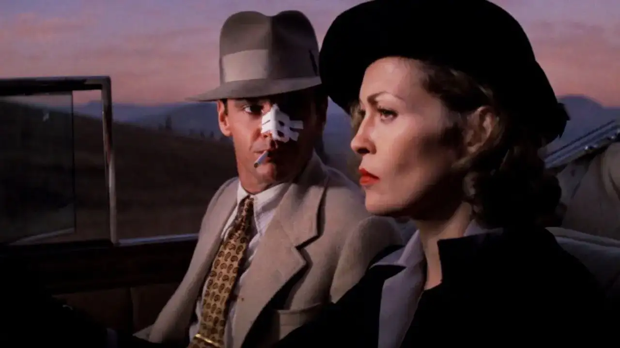 Jack Nicholson z plastrem na nosie i papierosem w ustach, obok Faye Dunaway w kapeluszu. Scena z jednego z filmów Romana Polańskiego.