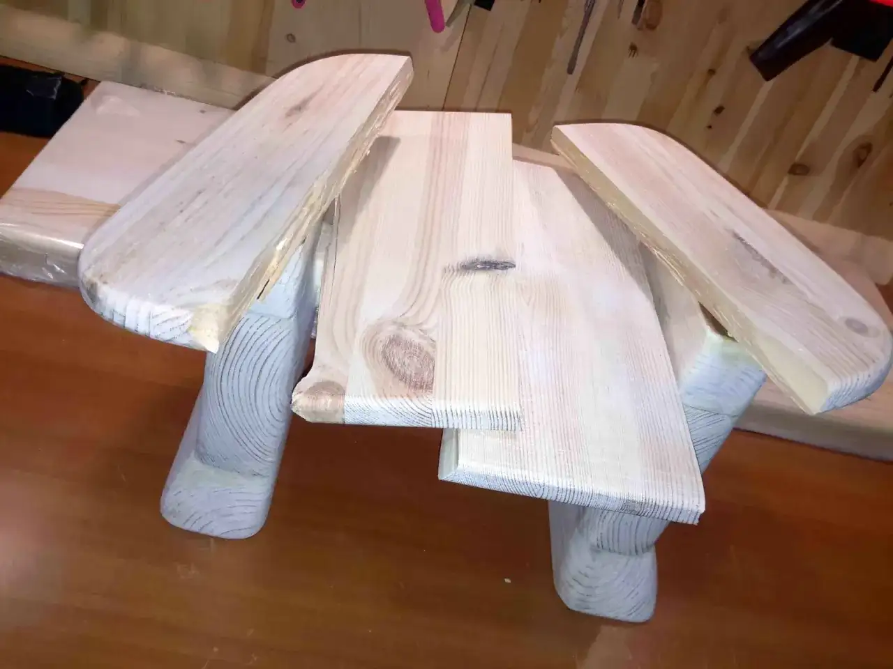 Drewniany taboret DIY, w trakcie budowy, z widocznymi słojami drewna i zaokrąglonymi elementami.