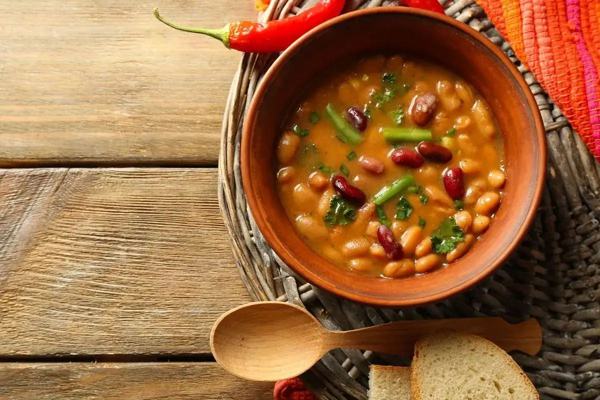 Miseczka fasolowej zupy, idealna na pytanie: jakie zupy przy cukrzycy? Z dodatkiem papryczki chili i ziół.