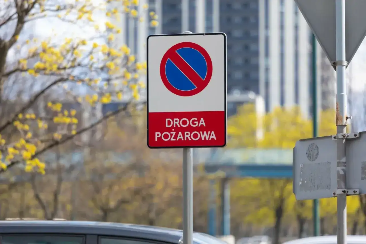 Znak zakazu zatrzymywania się na drodze pożarowej. Upewnij się, że droga jest wolna dla straży pożarnej.
